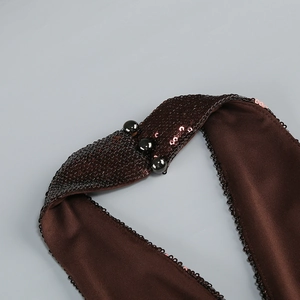 Detailed view of coffee brown sequin fabric with elegant black spherical button accents