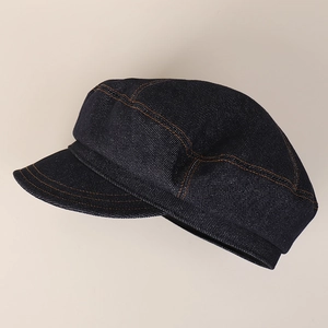 Detailed side view of dark blue denim newsboy cap featuring orange contrast stitching