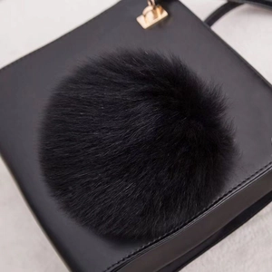Pendentif pompon en fourrure de renard noire sur un sac en cuir avec fermoir doré