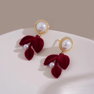 Elegant red flocked leaf earrings with pearls and gold metal frame on minimalist background
