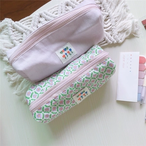 Primer plano de estuches de pana lila y estampado floral con cremalleras de metal grueso