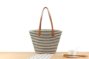 Close-up of striped woven tote bag with leather handles and decorative frayed edges