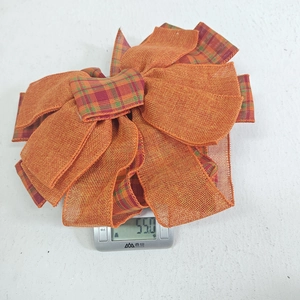 Weight detail showing orange plaid Thanksgiving bow on a scale at fifty-five grams