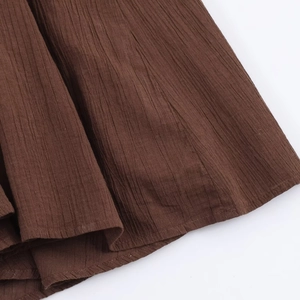 Detailed close-up of brown pleated fabric texture and professional stitching on midi dress