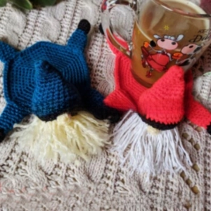 Detail of handmade crochet gnome coasters in blue and red with pointed hats and soft beards