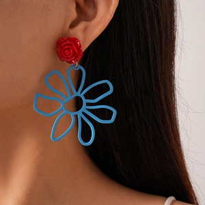 Détail de grandes boucles d'oreilles fleuries avec rose rouge et pendentif fleur bleue
