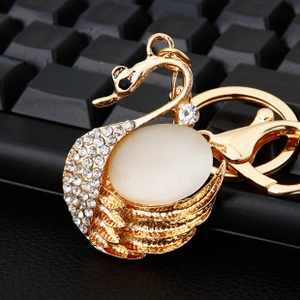 Macro shot of gold-plated swan keychain with white crystals and cat eye stone inlay