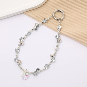 Macro shot of silver metal beads and iridescent heart pendant on a luxury phone charm