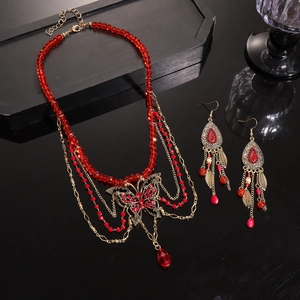 Detail of vintage red glass bead necklace and butterfly tassel earrings set with gold accents