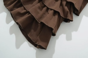 Close-up of dark brown ribbed knit fabric with layered ruffles and detailed stitching