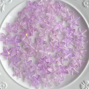 Close-up of purple gradient acrylic starfish beads with gold glitter for DIY jewelry making