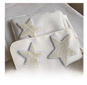 Detail view of plush star patches with fine stitching on a beige nylon messenger bag
