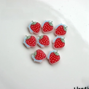 Detailed view of eight red resin strawberry charms with white dots and green leaves