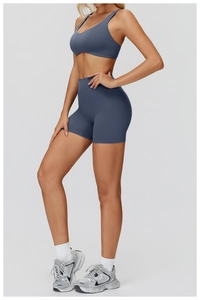 Side view of woman in dusty blue cross-back sports bra and high-waisted gym shorts set