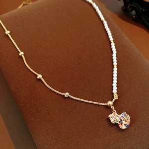 Detailed close-up of 18k gold plated chain with white pearls and a colorful zircon heart pendant