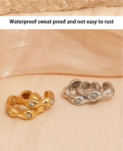 Detail of waterproof gold and silver wavy stainless steel rings with zircon on soft fabric