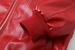 Detail of red PU leather jacket showing texture, white stitching and ribbed cuffs