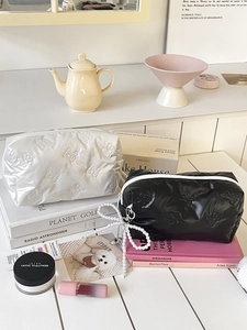 Close-up of quilted bow cosmetic bags with pearl pendants on a stylish vanity table