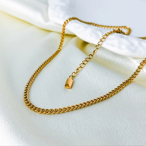 Detailed close-up of 14k gold-plated curb chain necklace on white silk background
