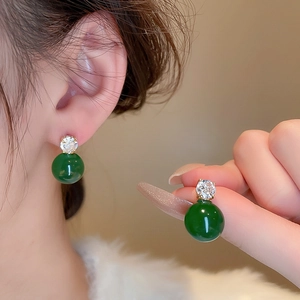 Detailed close-up of vintage green bead earrings with a clear zircon and gold metal base