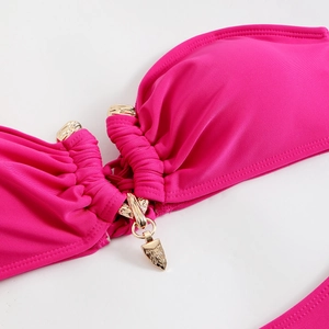 Gros plan du haut de bikini rose rouge avec tissu plissé et anneau en métal doré