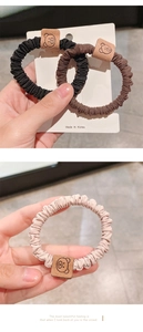 Detail of high-elastic bear hair ties in black, brown and beige colors with leather patch