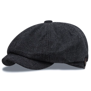 Detail of dark grey herringbone wool newsboy cap with leather side strap and metal rivet