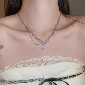 Detail of layered necklace with purple butterfly pendant and colorful gemstone beads