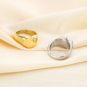 Macro shot of gold and silver heart signet rings resting on beige pleated silk fabric