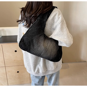 Sac bandoulière en denim noir en forme de croissant porté pour un look de banlieue