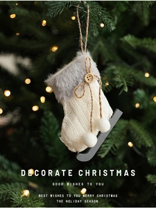 Detail of white knit ice skate ornament with grey faux fur trim hanging on Christmas tree