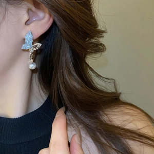 Détail macro boucle d'oreille papillon asymétrique avec perle et cristaux sur mannequin