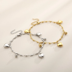 Beaded heart anklets in gold and silver steel with lobster clasp on beige surface