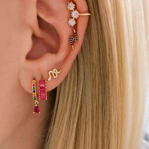 Close-up of ear styling with baguette zircon hoops, snake studs, and gold flower cuffs