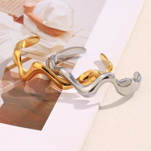 Detail of minimalist wavy stainless steel bracelets in gold and silver finishes