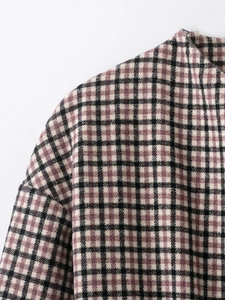 Close-up of the elegant purple plaid texture and stitching on a woman's long coat