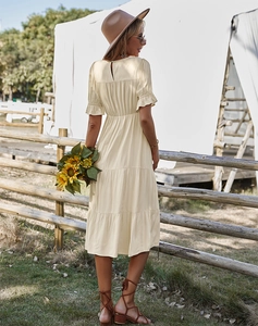 Vue détaillée de la robe beige en ligne A avec volants dans un décor naturel extérieur
