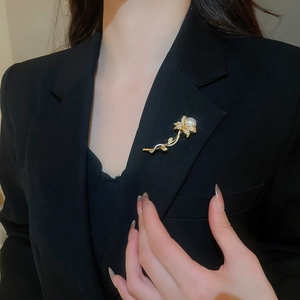 Detail of flower brooch with zircon stones and a large pearl on a black suit jacket