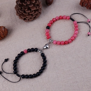 Close-up of 8mm natural stone magnetic heart bracelets for couples on rustic beige linen