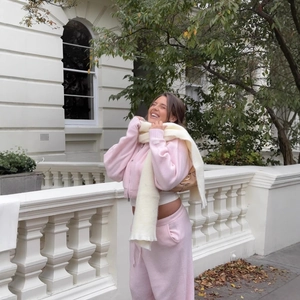 Women's pink zip hooded knit cardigan and trousers set with plush scarf in outdoor setting