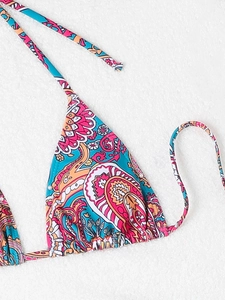 Detail of paisley print bikini top with halter neck ties on white plush surface