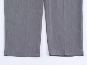 Gros plan de l'ourlet du pantalon gris montrant la texture fine du tissu sergé et détails
