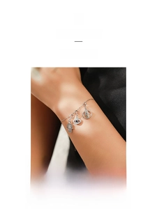 Detail of S925 silver bracelet with Hamsa Hand and Evil Eye charms on model wrist