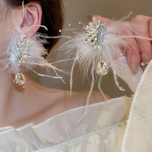 Detailed view of luxury earring with white feathers, crystals, and teardrop rhinestone