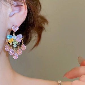 Detail of colorful tassel earrings with heart-shaped gems and teardrop pendants on model