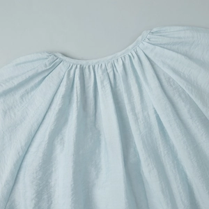 Close-up of gathered V-neck detail and ruffled texture on light blue chiffon blouse