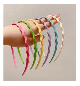 Detailed close-up of wavy resin headbands in various candy colors held by hand