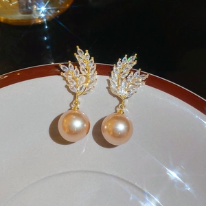 Detailed close-up of champagne pearl earrings with gold wheat motif and zircons