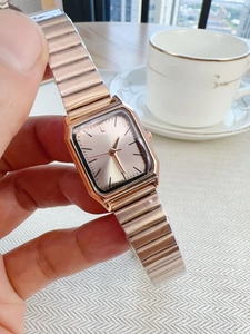 Detail of rose gold square watch with metal chain strap and elegant brand logo dial