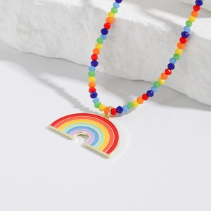 Close-up of rainbow beaded necklace with gold-edged heart pendant on a white stone